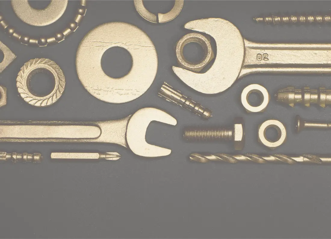 Spanners, washers and drill bits laid out on a dark workbench